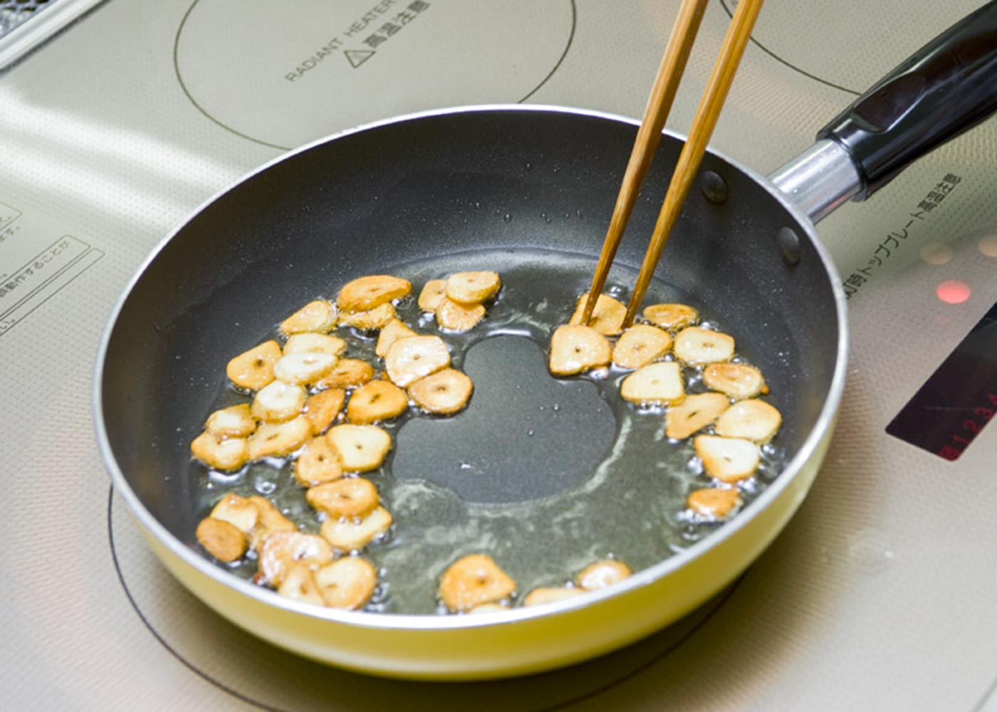 にんにくは両端を落として竹串で芯を取り、幅２㎜のスライスにする。鍋にオリーブ油を入れて弱火にかけ、にんにくを炒め始める。